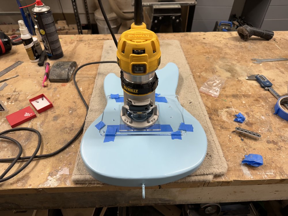 Another guitar body, this time one painted  blue, is sat on the workbench with the same template and palm-router set up as two pictures back.