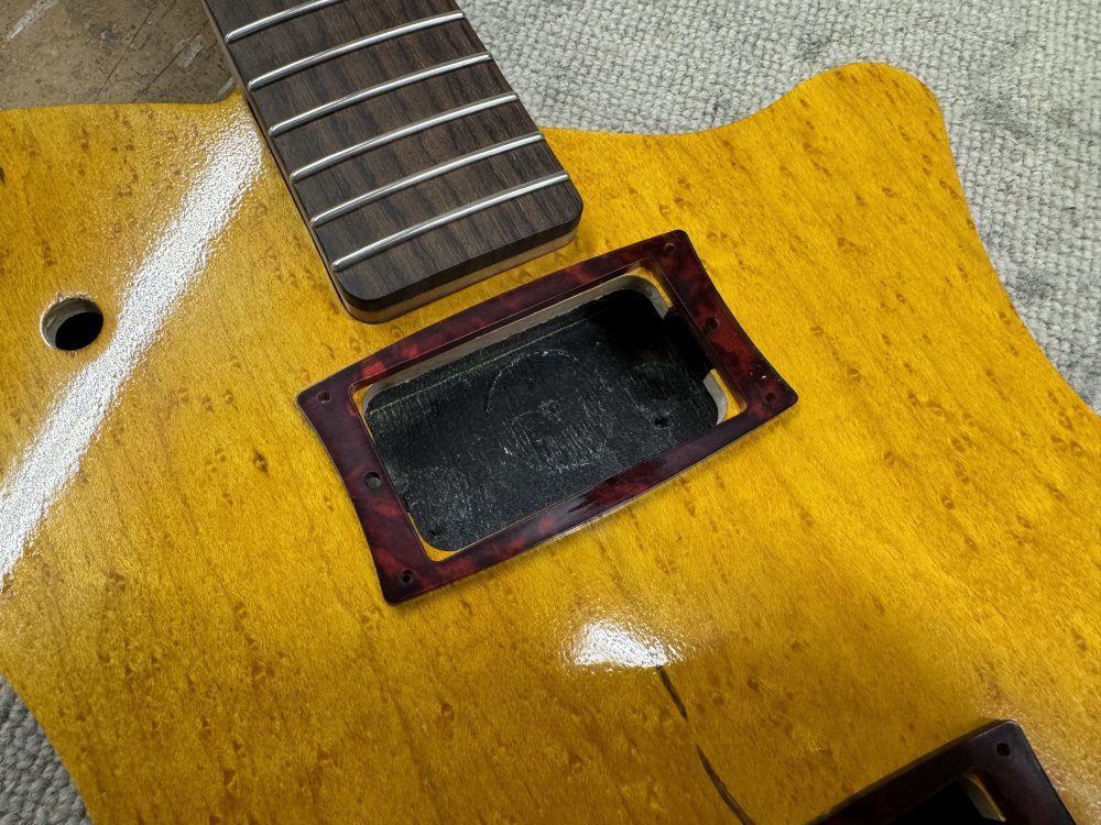 A close-up of the pickup mount rings shows that you can see wood from the top of the guitar on the inside, blocking where the pickups will go. 
