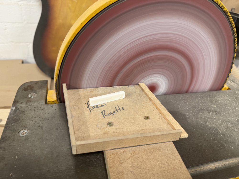 A photo of a spinning disk sander, and next to the face of the sander is a blank rectugular block of bone, about 5 cm by 1 cm by 0.5 cm