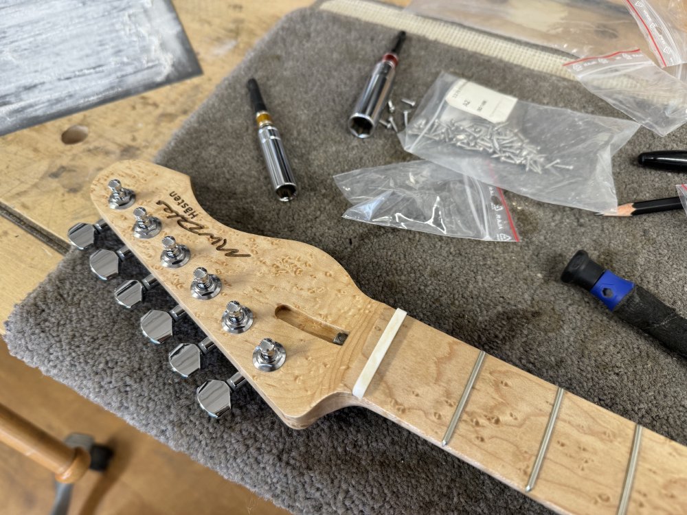 A view of a birds-eye maple neck with a bone nut in place.