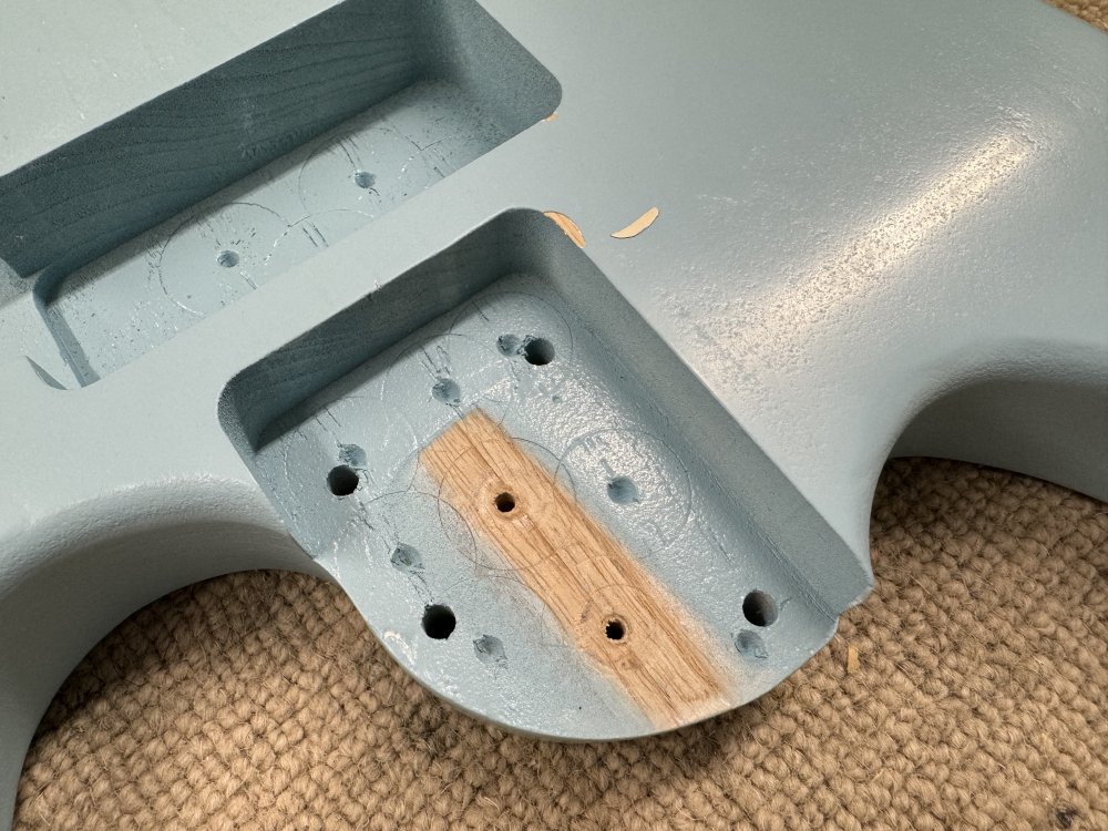 A photo of the neck pocket of the blue guitar, showing that a small bit of paint has chipped away around the edge where ideally it wouldn't have.