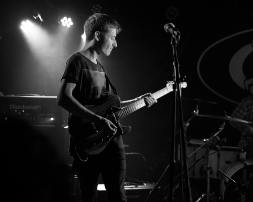 IKARI's lead guitarist Tris, on stage looking staisfied with what rock sound he's making from his guitar.