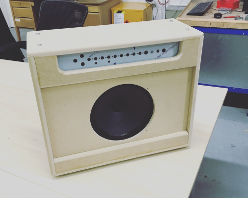 A photo of an unfinished amp combo cabinet that has been built. The speaker and metal component chassis are in place, but the body is just raw MDF and needs painting.
