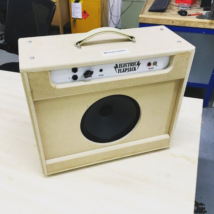 The amp combo cabinet once again sits on the workbench, but this time there is a plate with labels for the controls over the component tray.