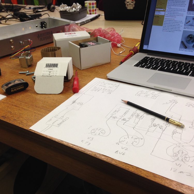 An A3 sheet of paper on a workbench next to a Mac laptop. On the paper is a crude circuit diagram of the amp circuit.