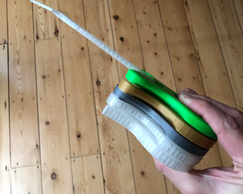 The author's hand, holding a stack of tiny 3D-printed guitar bodies, one of which has a neck also.