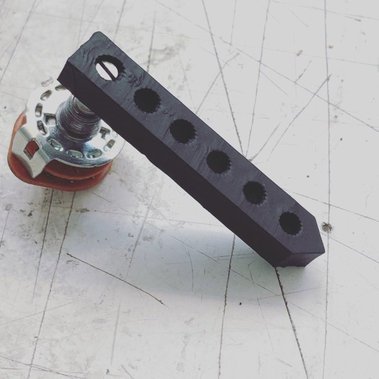 A black resin 3D-printed bar with knurled holes in it, into one of which is mounted a selector switch.
