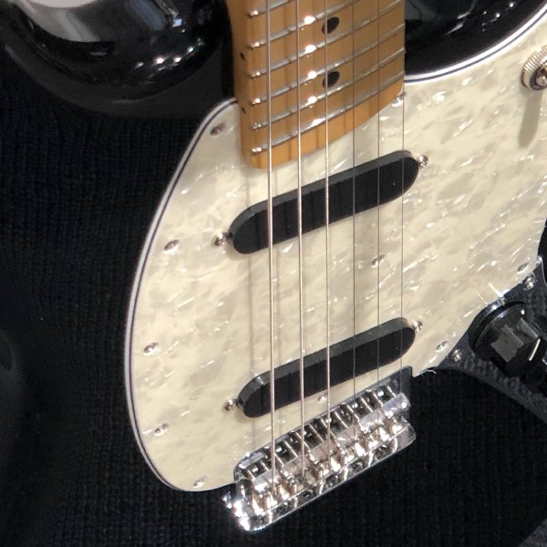 The close up of a Fender Mustang showing the bridge, where all the saddles are set to their maximum height.