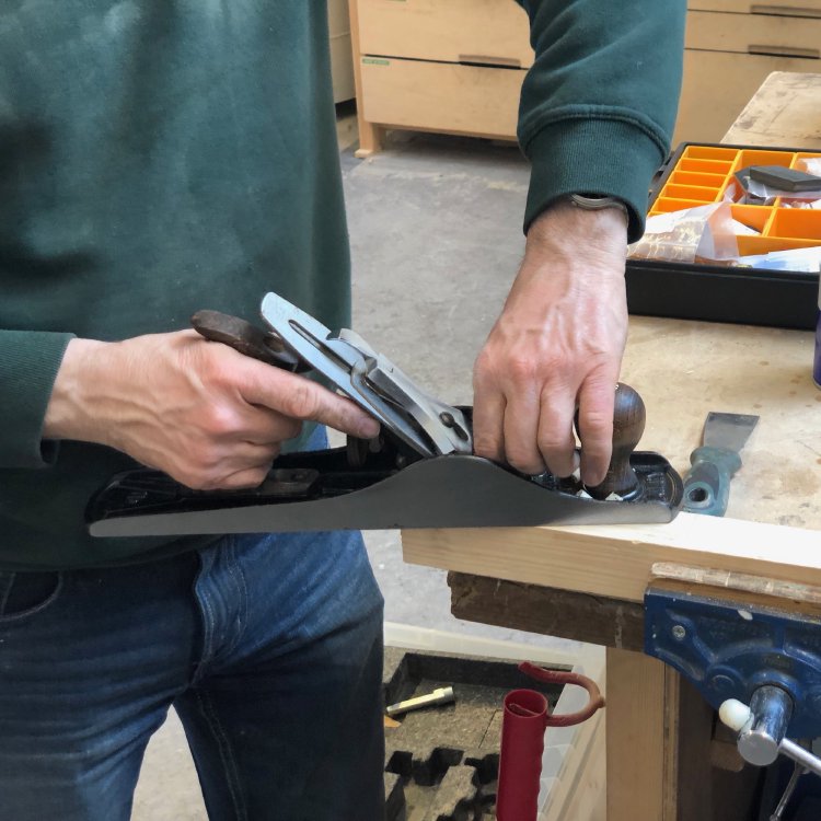 A shot of the hand-plane being tested on a block of scrap wood set in a vice.