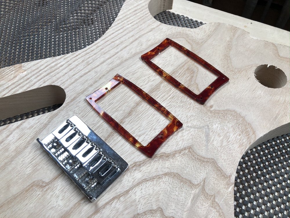A closeup of the body of the guitar being worked on earlier, with some tortoise-shell acrylic pickup mount rings placed on it.