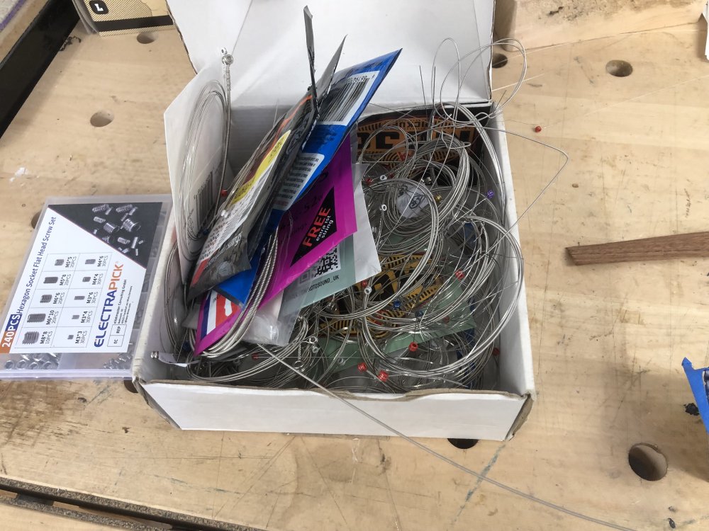 A small cardboard box sits on the workbench, into which is stuffed an unbelievable number of random strings.