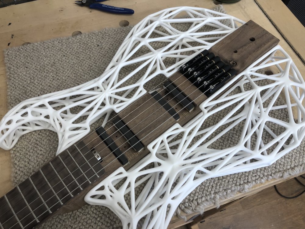 My älgen guitar sitting on the workbench, weith strings on, and 3D-printed sides mounted. It is still missing electronics.