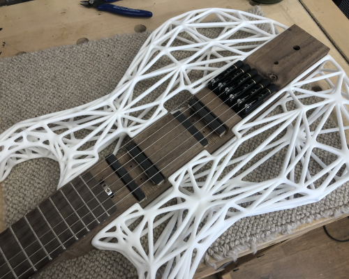 My älgen guitar sitting on the workbench, weith strings on, and 3D-printed sides mounted. It is still missing electronics.