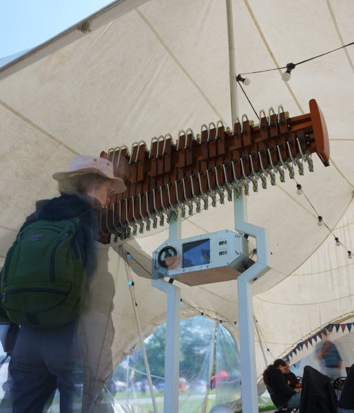 A photo of a oversized xylophone in a tent with someone playing it.