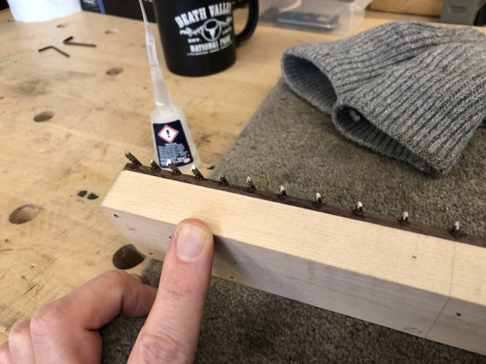 A picture of the side of the neck showing dabs of glue at the ends of the fret-wire where it is overhanging.