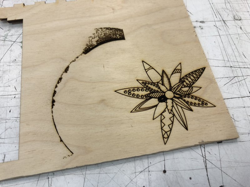 A bit of scrap plywood with two thing etched into it. Firstly a dark but well defined flower shape, and then an aborted attempt to cut an arc made up from thousands of tiny lines.
