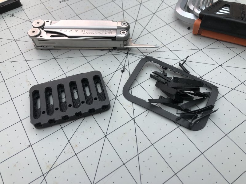 The same 3D-print as before, but with a bit of a hair-cut, sat next to a leatherman which was used to apply the hair-cut, and a pile of discarded plastic that was removed from the print.