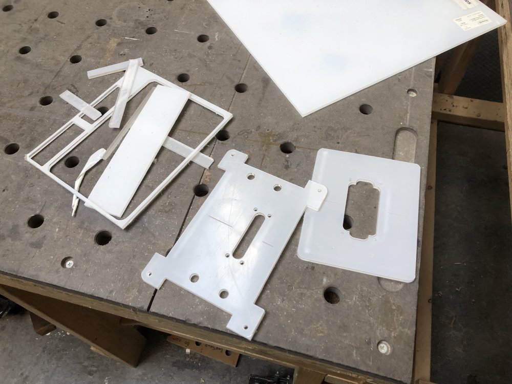 A pile of acrylic shapes scattered on a workbench after I've finished separating them using the bandsaw.