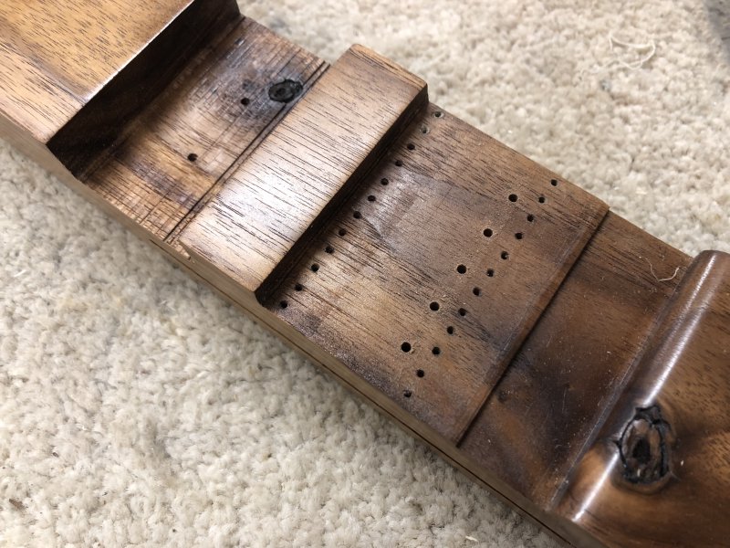 The same bit of guitar, where you can see 24 tiny screw holes that held the original bridge part, and five larger holes in a row for the new bridge.