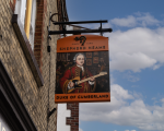 The pub sign for The Duke of Cumberland which shows a painting of a 17 or 18th century duke playing a Fender Telecaster with a jazz ensemble behind him.