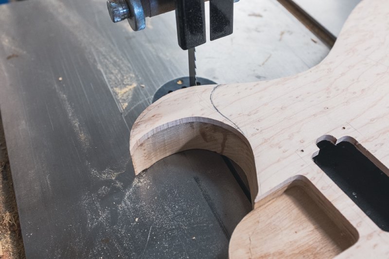The body sat on the bandsaw table, with the blade lined up to cut a chunk off the top.