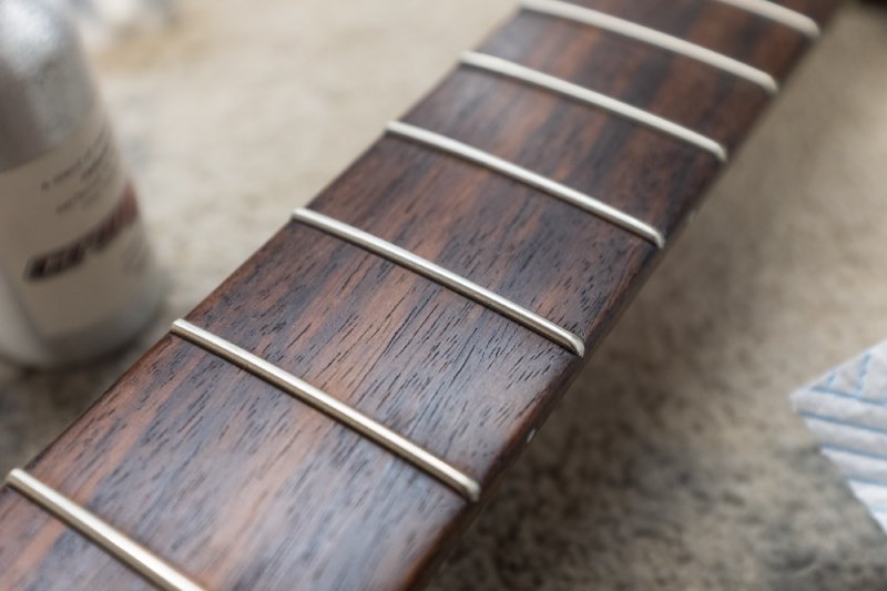 A close up of the rosewood fretboard, showing the colour and texture of the wood.
