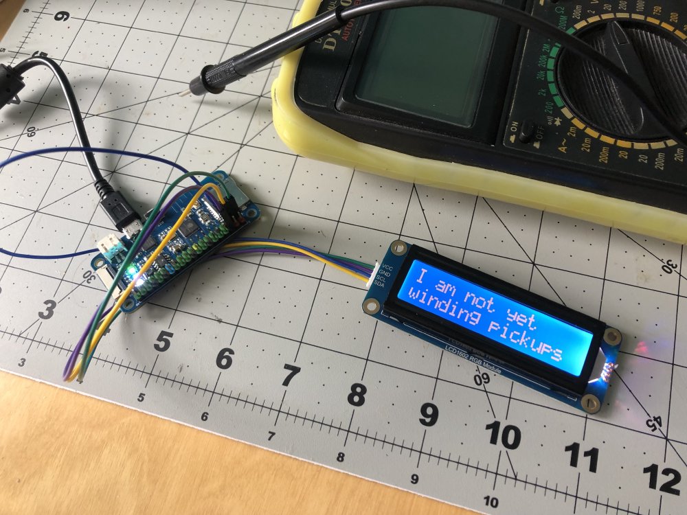 A small ESP32 dev board plugged into an LCD text panel that is displaying 'I am not yet winding pickups'.