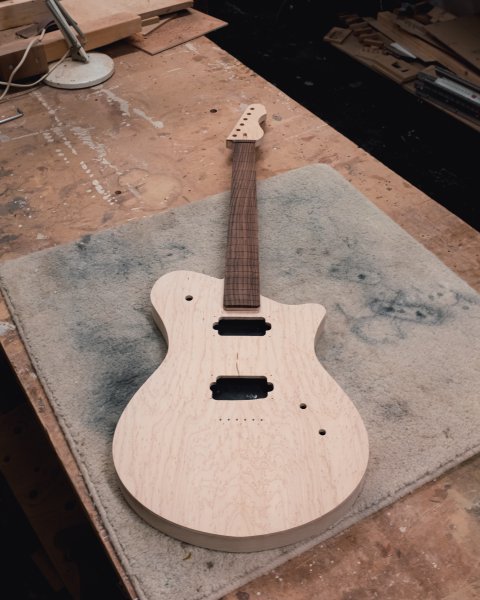 The work in progress verkstaden guitar sits on the workbench, with both the body and neck together to let me see the overall shape.