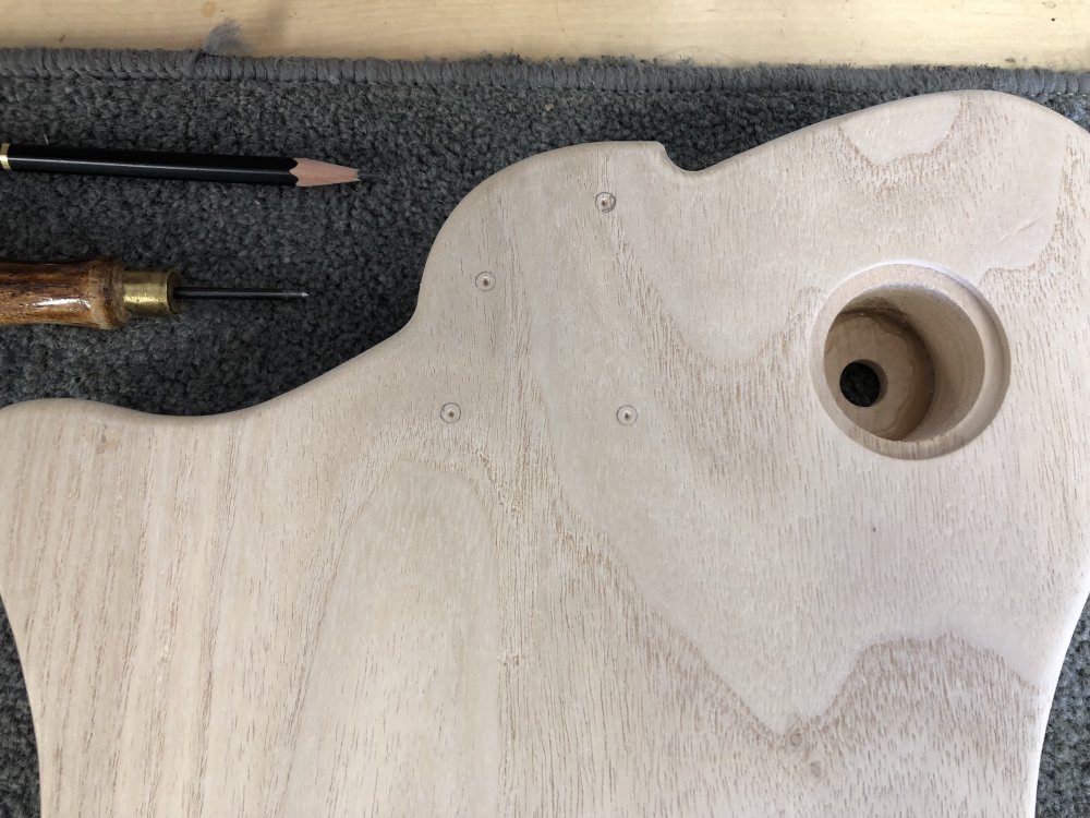 A close up of the neck area on the back of the guitar body, showing where the marks have been made ready for drilling the four holes for the screws to attach the neck.