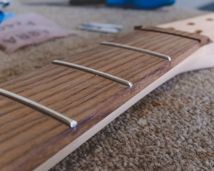 A close up on the first three frets on the neck with two rounded nicely at the end, and one still to be shaped.
