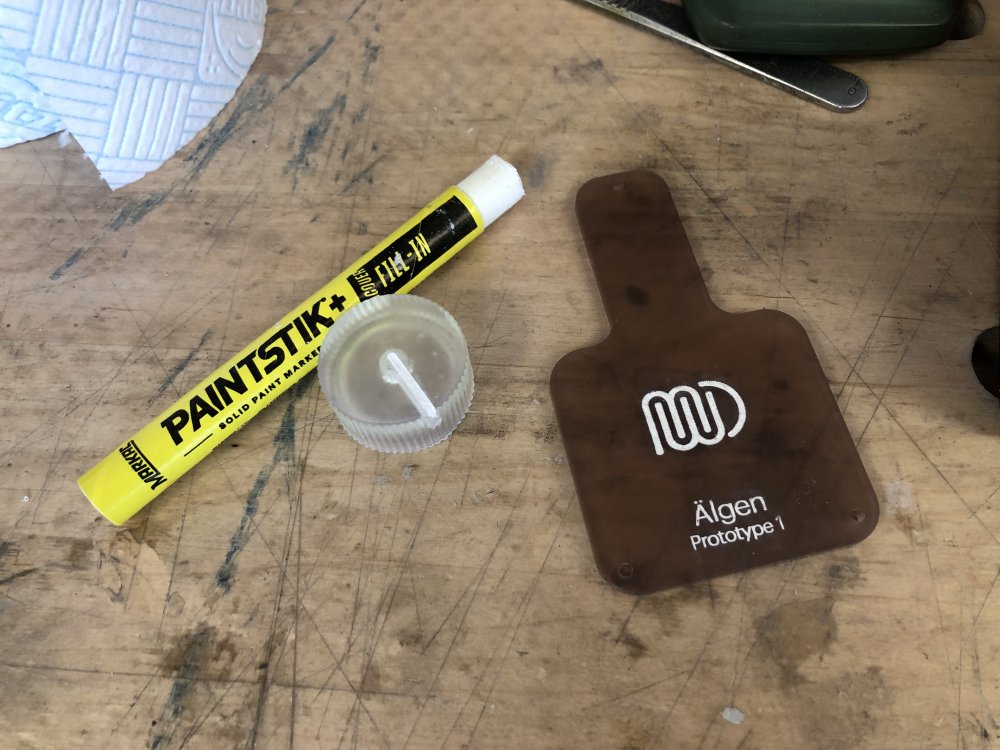On my workbench sits a thing that looks like a chonky white wax-crayon, but is labelled as a Paintstik+, and beside that is a cylindrical volume control with the indicator line filled in white, and a dark orange acrylic back-plate for a guitar with some branding on it also filled in white.