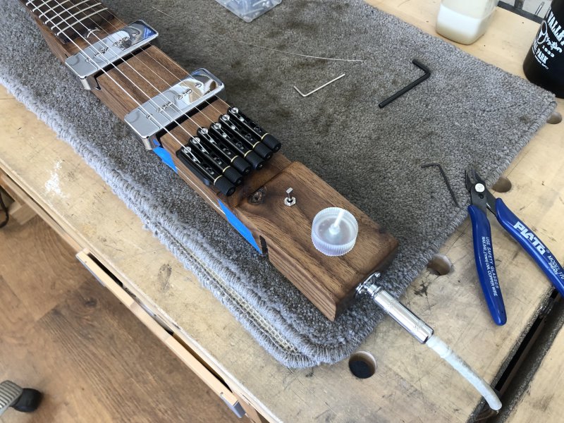 A close up on the tail of the Älgen guitar sat on the workbench, with the new 3D-printed volume control installed next to the pickup selector switch.