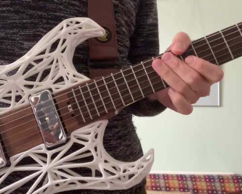 A close up of älgen guitar being held by me, showing the chrome pickups and rosewood fretboard.