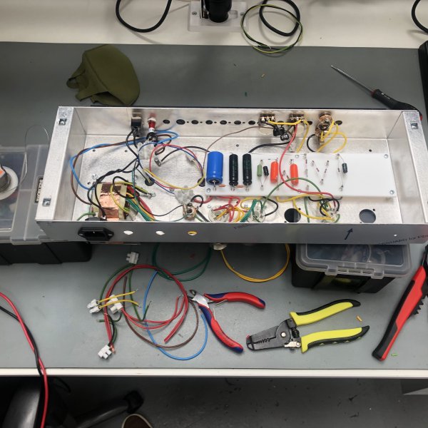 The same view inside the chassis of the amp as before, but now there's a lot less wire, with things looking comparatively neater. Beside the chassis is a pile of bits of wire and some wire cutting and stripping tools.
