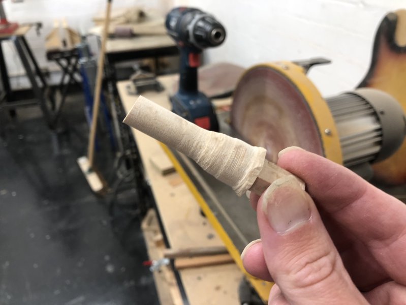 I'm holding up what looks like a tapered peg of wood, with the last inch or so being of roughly uniform diameter.