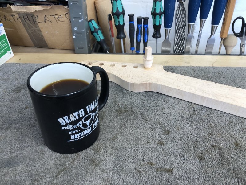 A fresh mug of coffee sits besides the neck, where you can see the plug is in place and the wood glue has now dried.