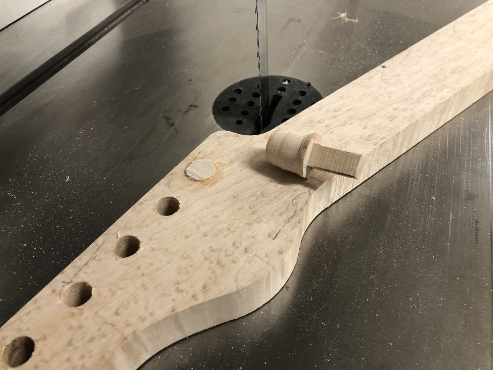 The neck sits on the band-saw table with the top of the plug sat next to it having been cut off.