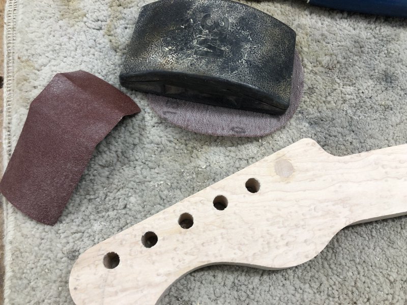 A close up on the back of the headstock, where you can see the five remaining holes and the one plugged hole. The wood grain on the plugged hole does not match the rest of the neck, but there is no gap around it, showing a near perfect fit.