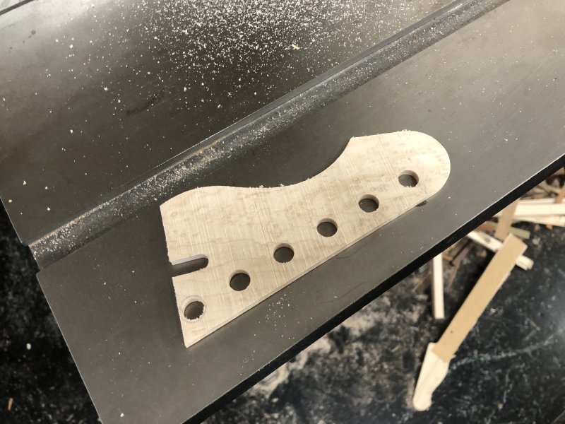 The bit of wood that was removed from the headstock sits on the workbench table.