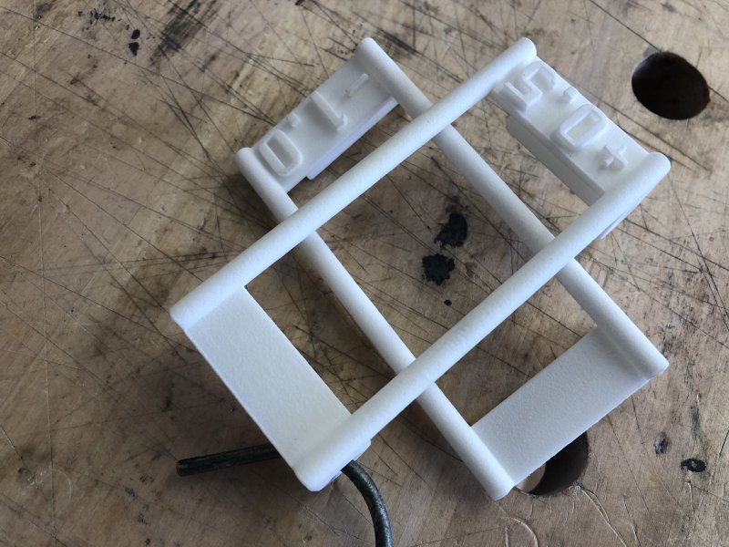 Two white nylon 3D-prints made of beams and joints (I was testing something structural with these prints, they're not actually meant to be anything in particular) sit on the bench, looking identical in colour and texture.
