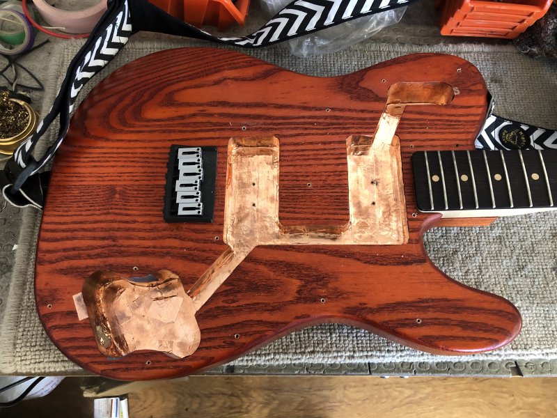 A view of the body of the guitar with the pick-guard and all the electronics components removed. You can see all the channels within the body, which are covered in a tarnished looking copper tape.