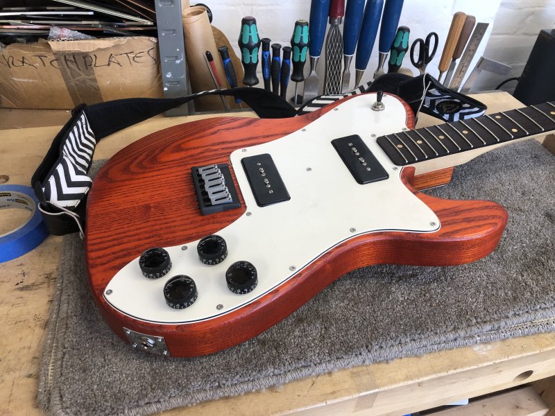 The guitar sits re-assembled on the workbench with all the new copper tape and electronics hidden behind the white pick-guard.