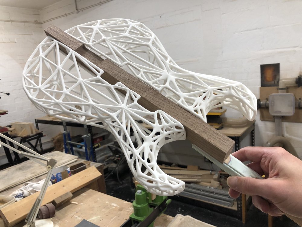 I'm holding the rod that will be in the clamp, and mounted into the clamp are the two halves of the 3D-printed body of the guitar.