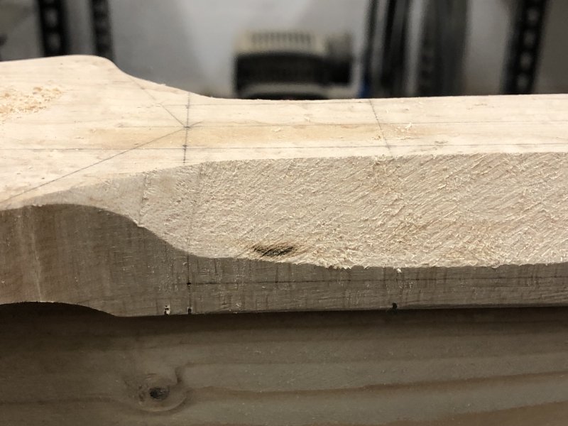 A close up of the head-stock end of the neck, and in the carved section you can see a small patch, about a centimetre long, that is very dark compared to the pale maple wood.