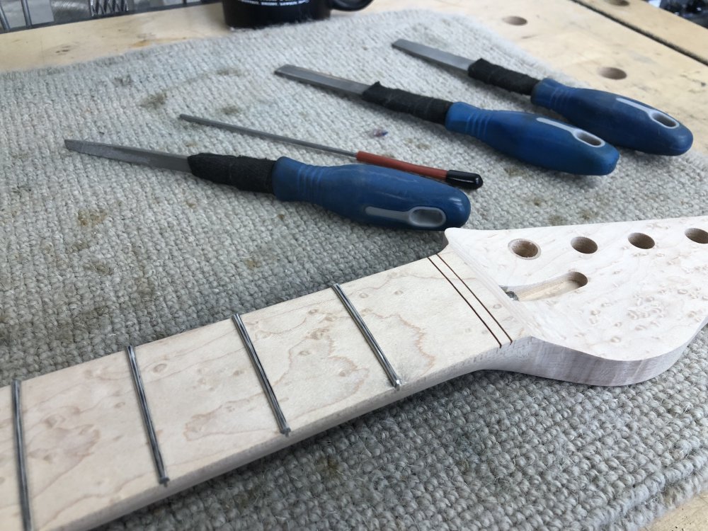 The neck now sits on another workbench, and there is a small set of conventional files next to it. If you look closely, one fret end has been dressed.