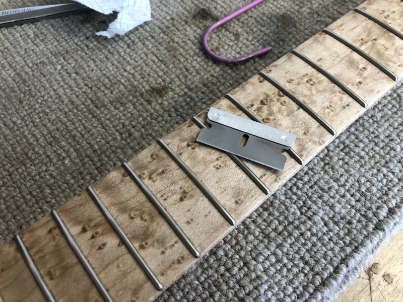 Another close up of the neck, this time with a razor blade balanced on the frets.
