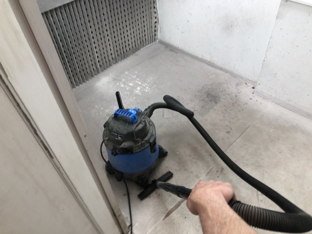 A picture of the floor of the spray-booth in which you can see my other hand holding a blue vacuum cleaner.