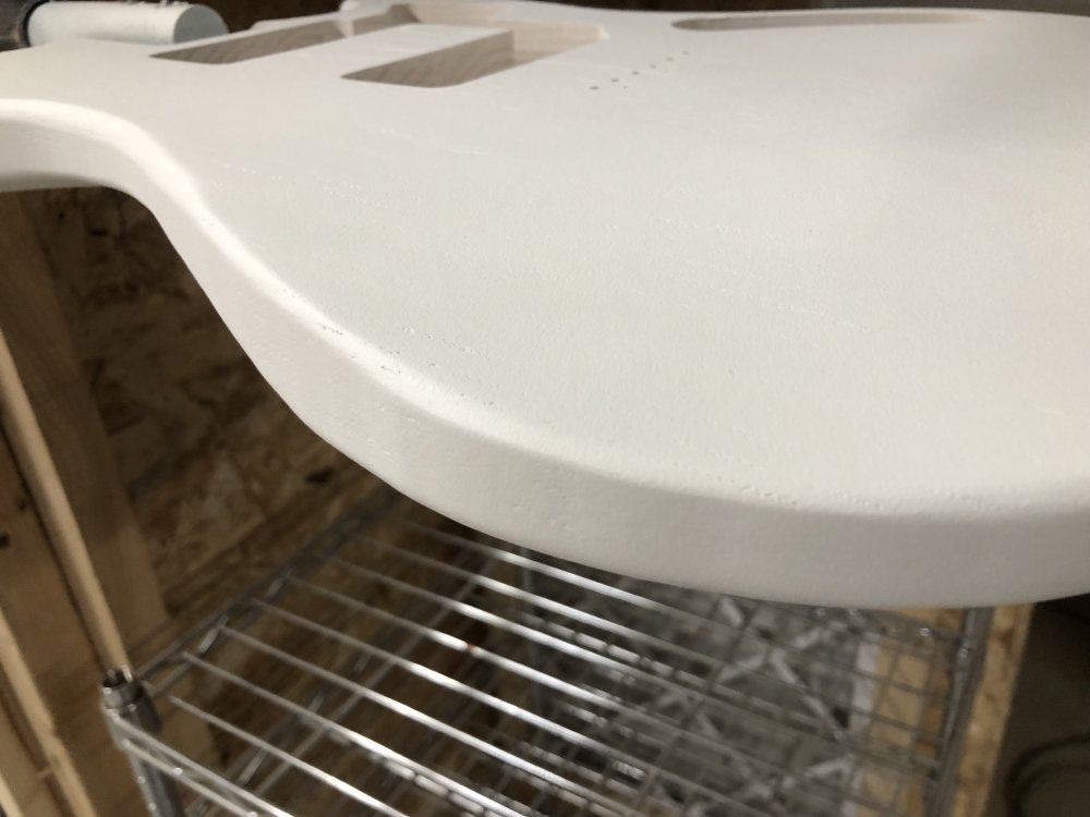 A close up on the edge of one of the sprayed bodies, which is covered in white primer. You can just about make out the sweep of the curve has some slight faceting to it.