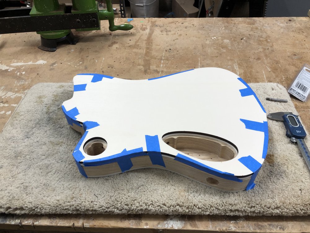 The double-decker template sits on top of a guitar body, held in place by masking tape.