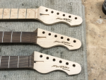 A close-up of three headstocks, with my signature and guitar's name laser etched into the headstock.